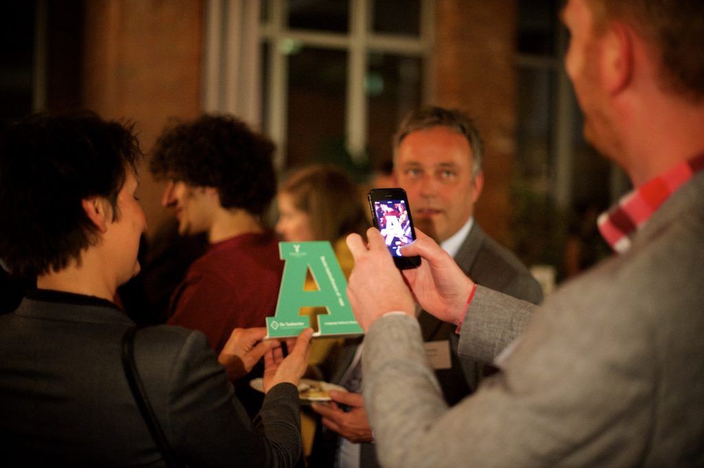 Foto van iemand die met zijn telefoon een foto neemt van een Lia award.
