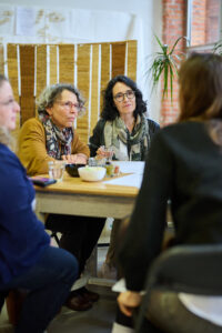 foto van mensen die aan tafel iets aan het eten zijn en aan het praten zijn met elkaar.
