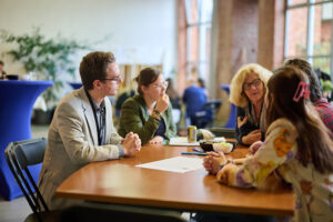 foto van mensen die samen aan tafel zitten en aan het praten zijn.