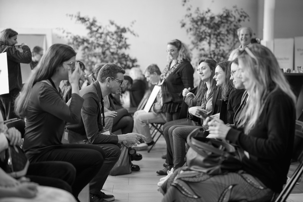 Zwart-witfoto van mensen die naast elkaar zitten en met elkaar praten.